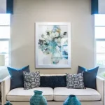 Phòng khách với sofa trắng, gối tựa xanh navy và rèm cửa hai bên cửa sổ