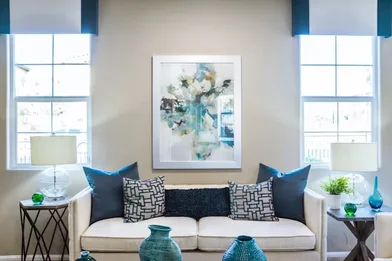 Phòng khách với sofa trắng, gối tựa xanh navy và rèm cửa hai bên cửa sổ