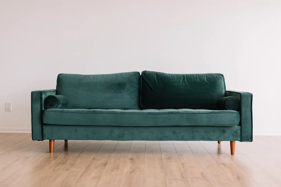 Sofa nỉ màu xanh rêu ba chỗ ngồi kê sát tường trắng trên sàn gỗ sáng
